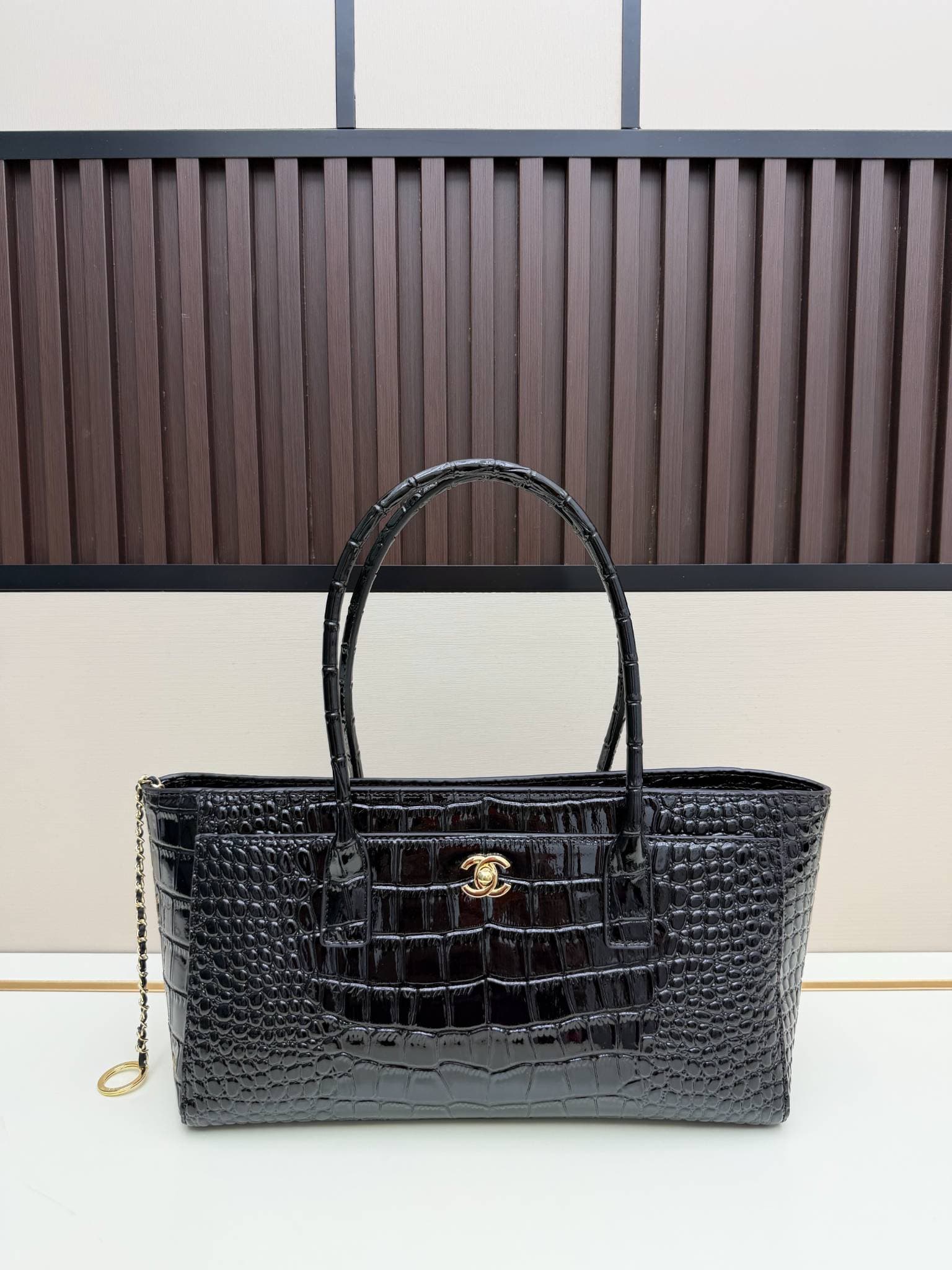 Sac cabas en cuir verni façon croco avec poignée supérieure ornée du logo en métal. Plusieurs couleurs. Grand format, idéal pour les trajets qu