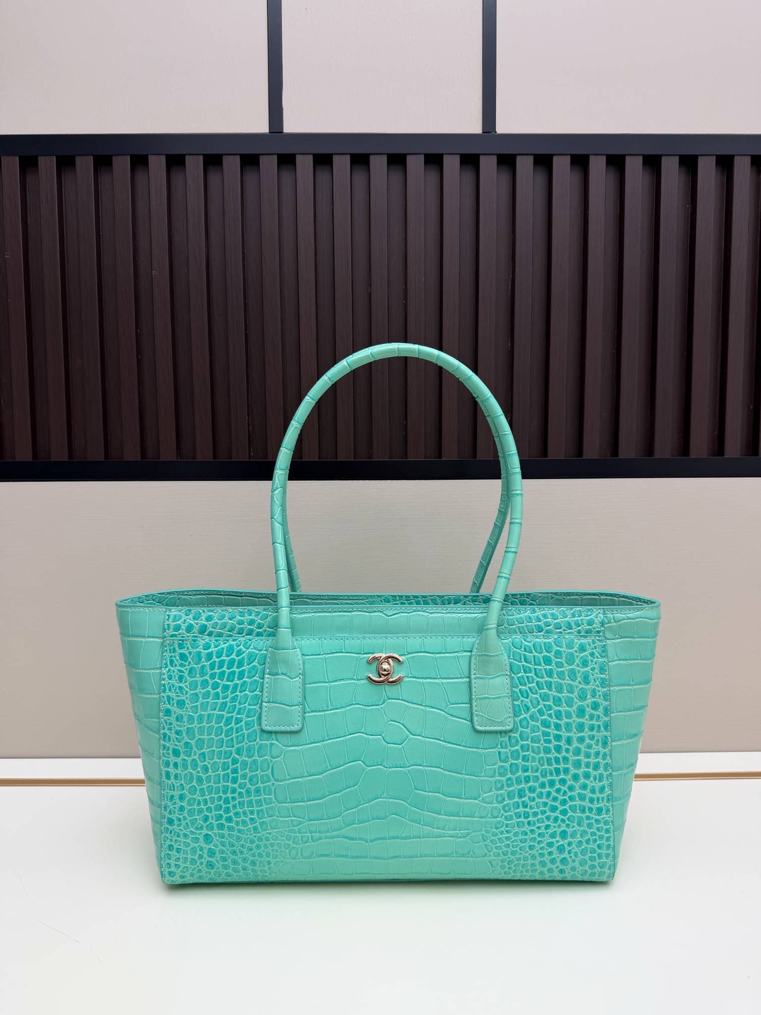 Sac cabas en cuir verni façon croco avec poignée supérieure ornée du logo en métal. Plusieurs couleurs. Grand format, idéal pour les trajets qu