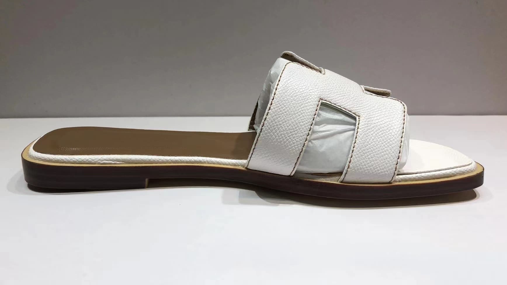 Les femmes portent du cuir avec des pantoufles plates et des sandales