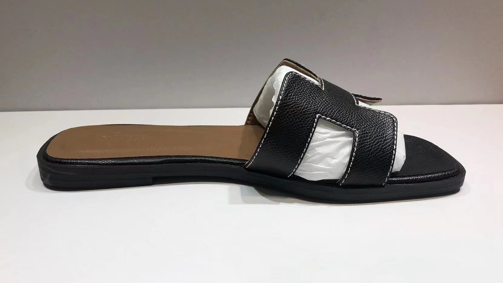 Les femmes portent du cuir avec des pantoufles plates et des sandales